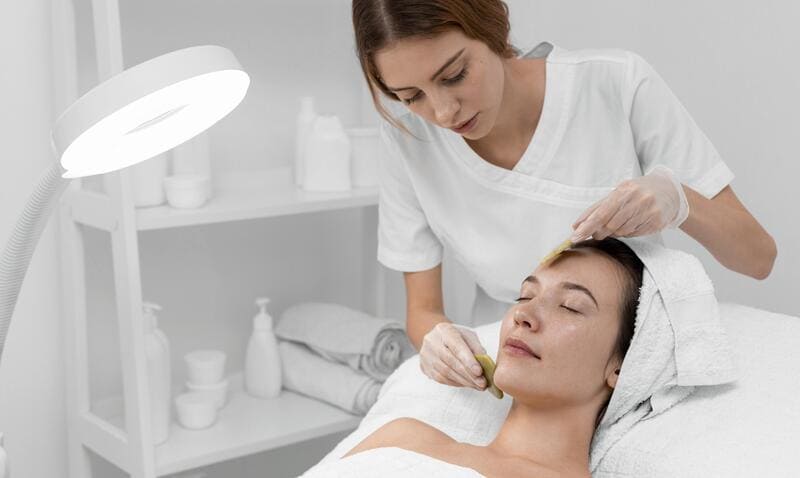 Esteticista conduz tratamento para estimular a produção de colágeno no rosto da paciente.